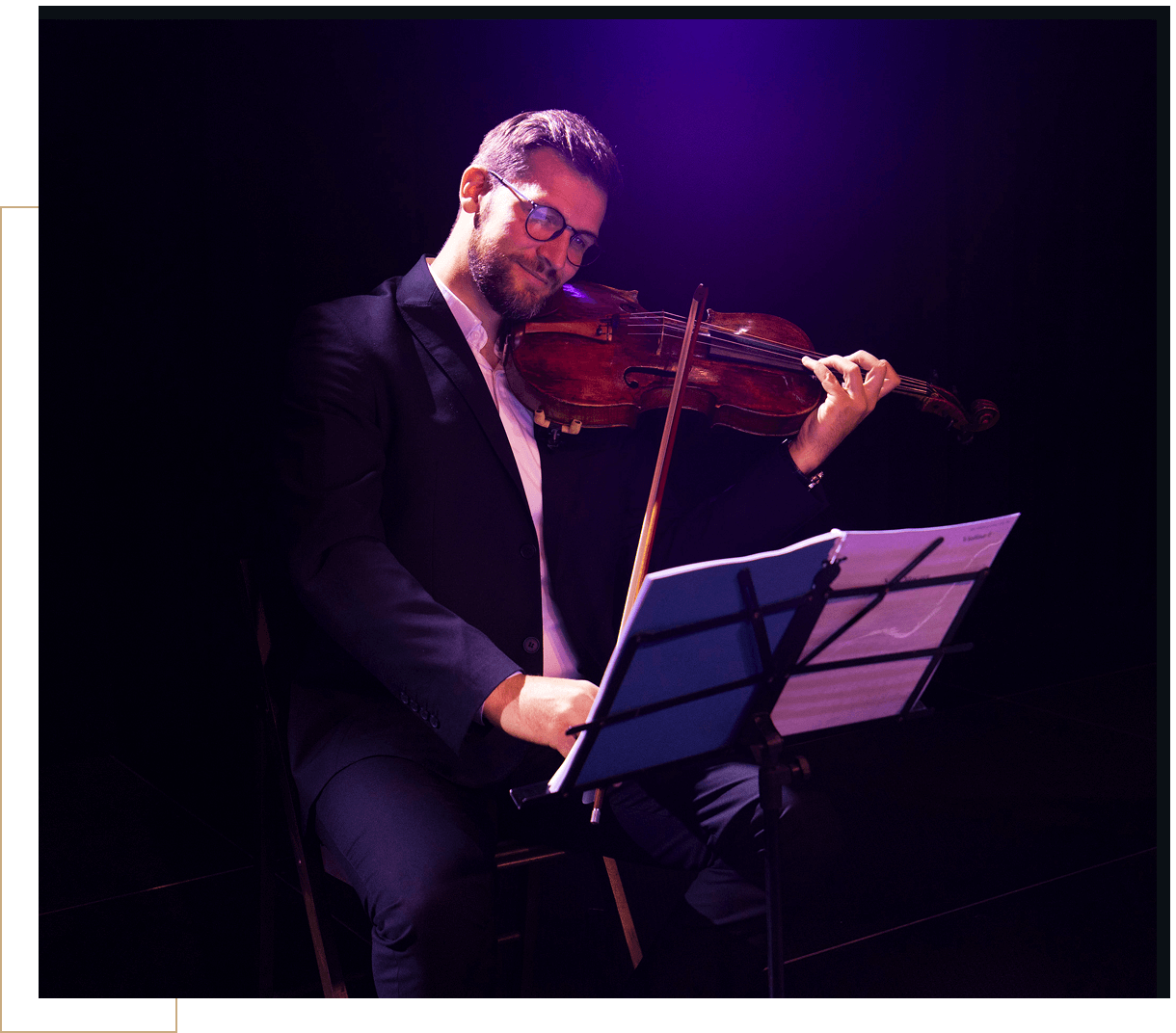 Man playing violin on stage with sheet music.