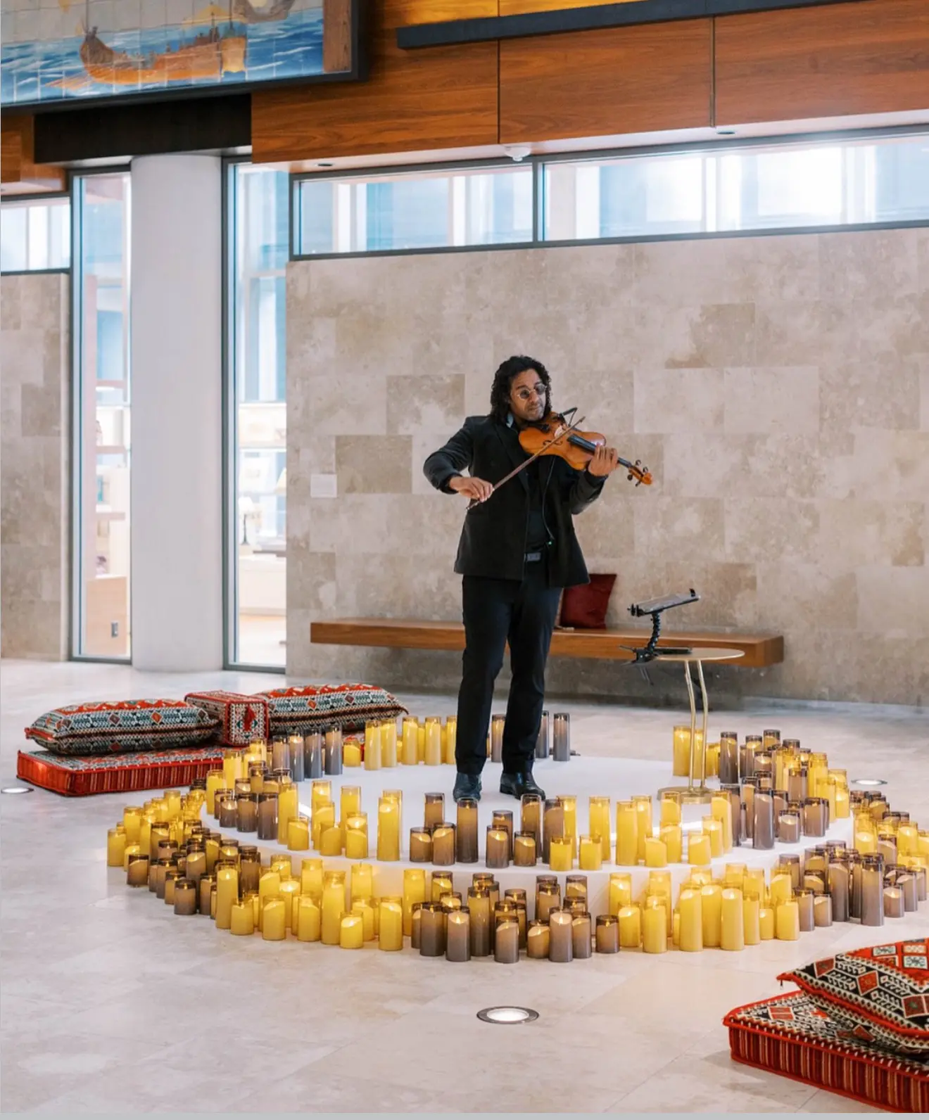 A violinist performing amidst a circular arrangement of lit candles.